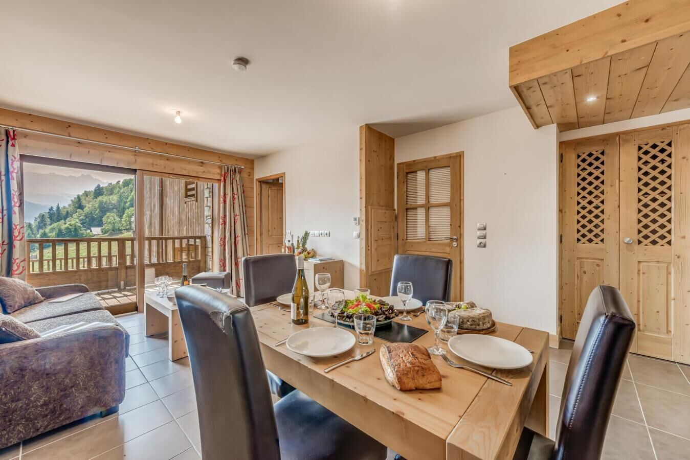 A dining area with a wooden table set for four, surrounded by chairs.