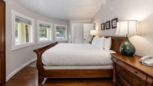 A bedroom with a large bed, a wooden dresser, a lamp, and a telephone.
