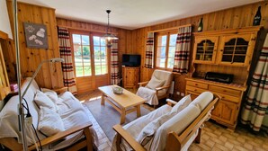 Una habitación acogedora con paredes de madera, televisión, aparador de madera y un banco.