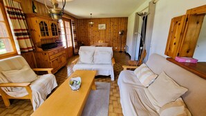 Una habitación acogedora con paredes de madera, un sofá, una mesa de madera y un armario.