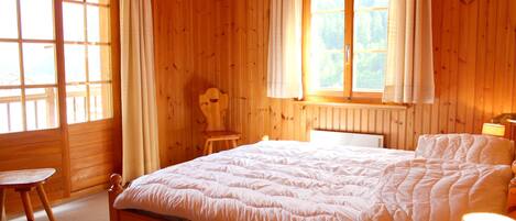 Une pièce en bois avec un lit, une chaise et une fenêtre avec des rideaux.