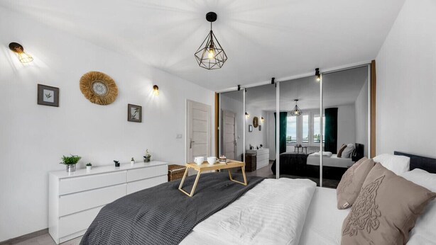 Un dormitorio moderno con cama, mesita de noche, cómoda y un espejo grande.