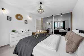 Une chambre à coucher moderne, avec un lit, une table de chevet, une commode et un grand miroir.