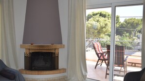 Een woonkamer met een open haard, een bank en uitzicht op het terras.