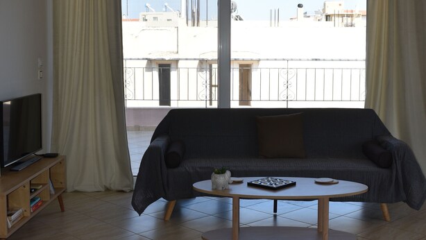 Een woonkamer met een bank, een salontafel en een televisie op een houten dressoir.