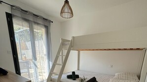 Une chambre avec un lit superposé, un bureau en bois, une échelle et un luminaire suspendu.