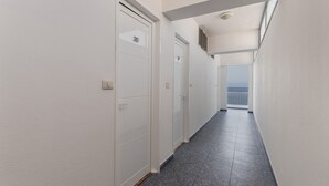 A corridor with white doors, a tiled floor, and a view of the sea through a window. - Studio 'Martin - 32' with Sea View, Balcony and Wi-Fi (Puerto de Naos)