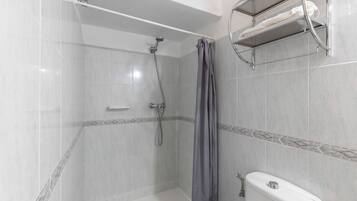 A shower with a showerhead, a curtain, and a towel rack with a towel.