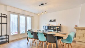 A dining area with a table set for four, chairs, a bookshelf, and a fireplace. - Grande Maison avec Jardin, Parking, proche de la Plage (Les Sables-d'Olonne)
