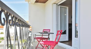 A balcony with a table and chairs, a sliding glass door, and a metal railing.