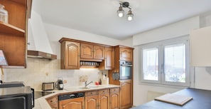 A kitchen with wooden cabinets, a built-in oven, a dishwasher, and a window with a view.