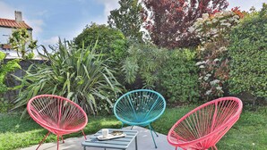 Three colorful wire chairs, a small table, and a white mug on a metal table in a garden setting. - Grande Maison avec Jardin, Parking, proche de la Plage (Les Sables-d'Olonne)