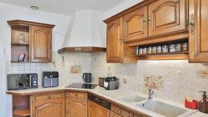 A kitchen with wooden cabinets, a microwave, a coffee maker, a toaster, and a dishwasher. - Grande Maison avec Jardin, Parking, proche de la Plage (Les Sables-d'Olonne)