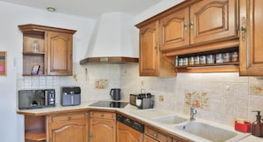 Una cocina con armarios de madera, microondas, cafetera, tostadora y lavavajillas.