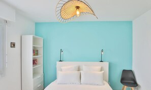 A bedroom with a bed, two bedside lamps, a white wardrobe, and a unique ceiling light fixture.