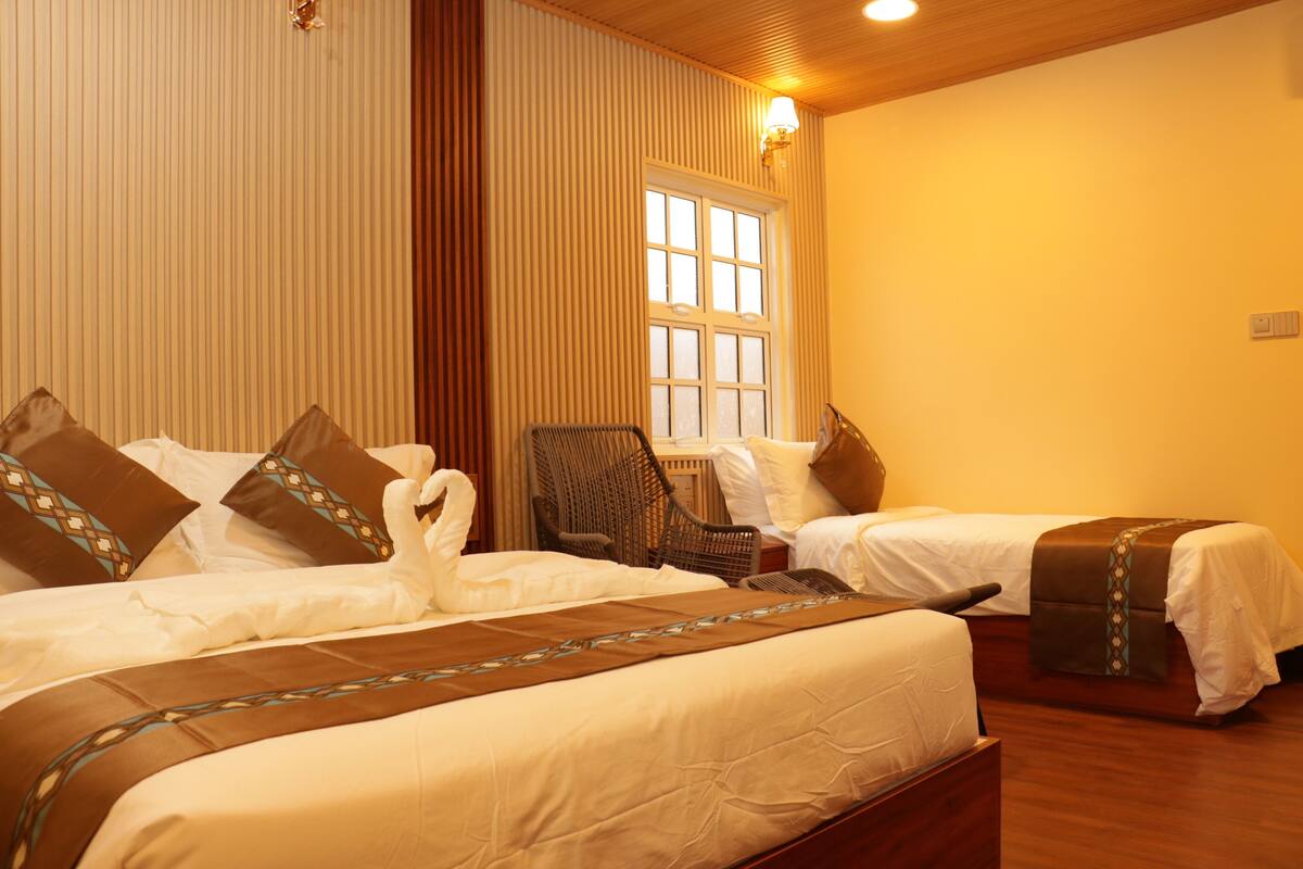 Habitación de hotel con dos camas, ventana, silla y lámpara.