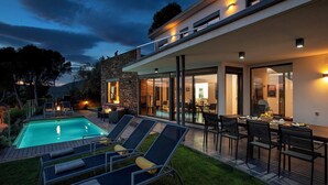 Ein modernes Haus mit Swimmingpool, Sitzgelegenheiten im Freien und Essbereich.
