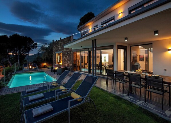 Una casa moderna con piscina, mobiliario exterior y zona de comedor.