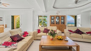 Ein geräumiges Wohnzimmer mit zwei beigen Sofas, einem Holztisch und Blick ins Freie.