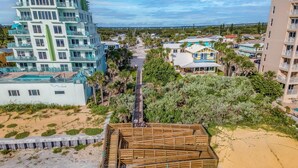 A coastal residential area with a multi-story building, a wooden structure on the beach, and a clear view of the ocean.