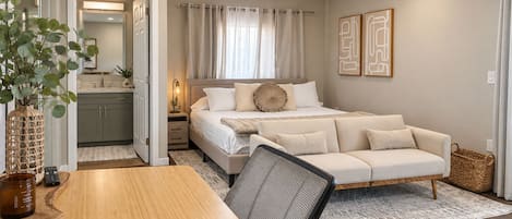 Unwind in this inviting bedroom suite featuring a plush bed, cozy loveseat, dedicated workspace, and convenient ensuite bathroom.