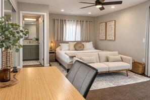 A bedroom with a bed, a sofa, a dining table, and a ceiling fan. - Modern 3-bed Hub resort / ping pong & pool table. Game room (San Diego)