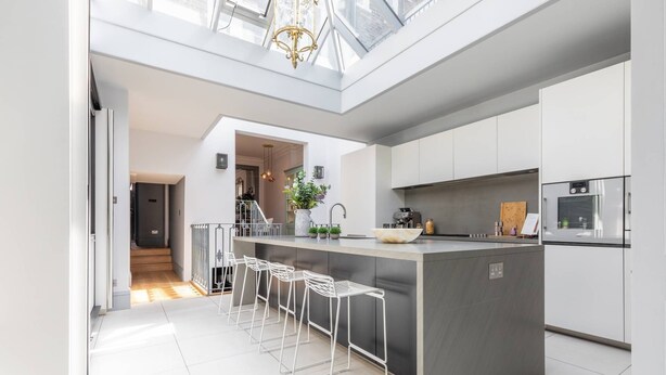 A modern kitchen with a central island, bar stools, and a built-in oven. - Eccleston Street III by onefinestay (London)
