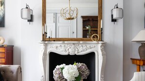 A living room with a white fireplace, a large mirror above it, and a glass coffee table in the center. - Eccleston Street III by onefinestay (London)