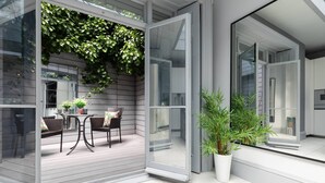 A modern patio with a glass door, a dining area with a table and chairs, and a potted plant. - Eccleston Street III by onefinestay (London)