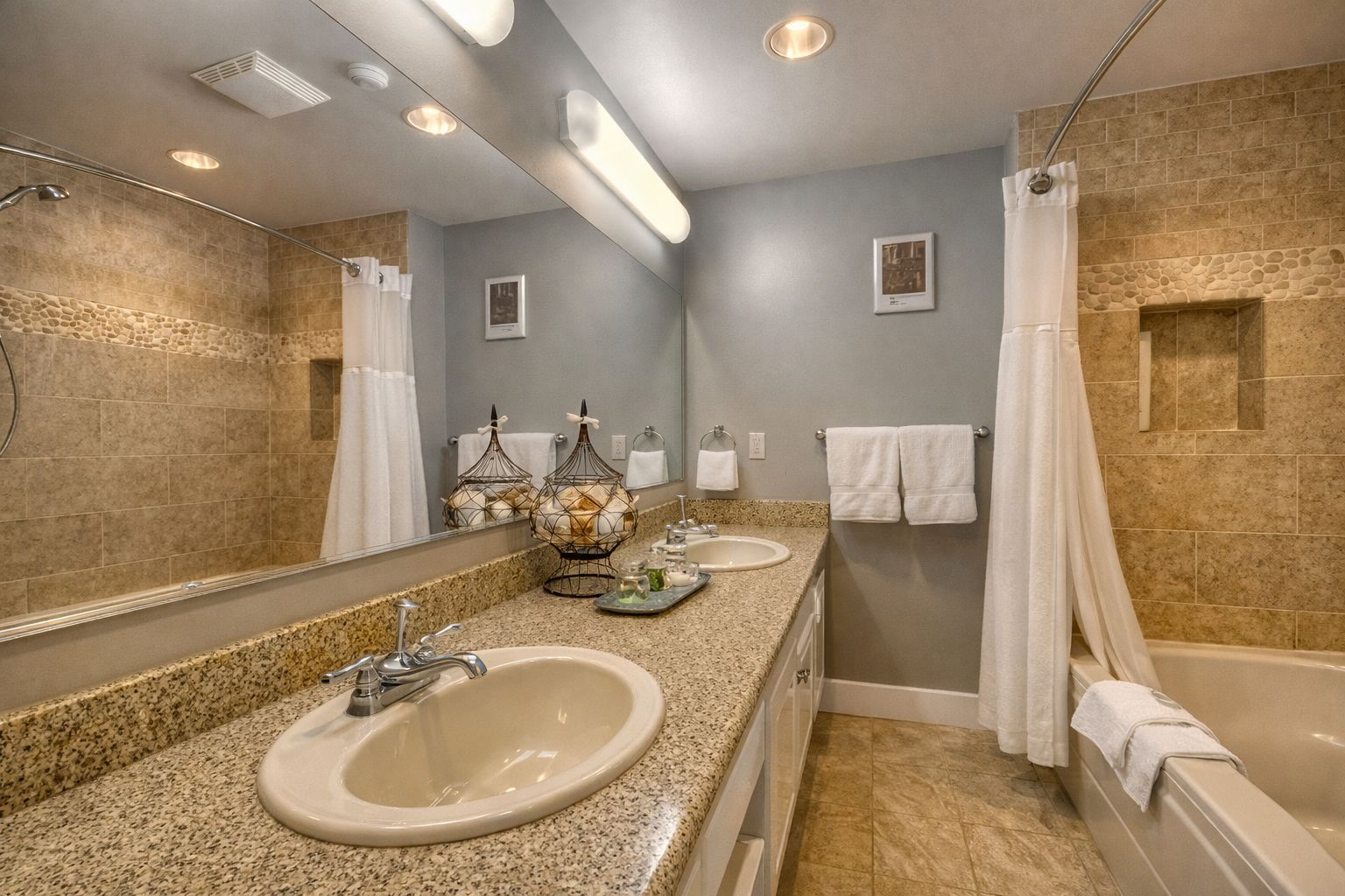 Une salle de bain avec deux lavabos, une baignoire, une douche et un grand miroir.