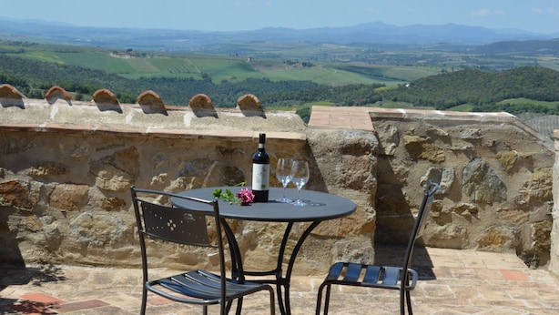 A stone wall with a table and chairs overlooking a scenic landscape.