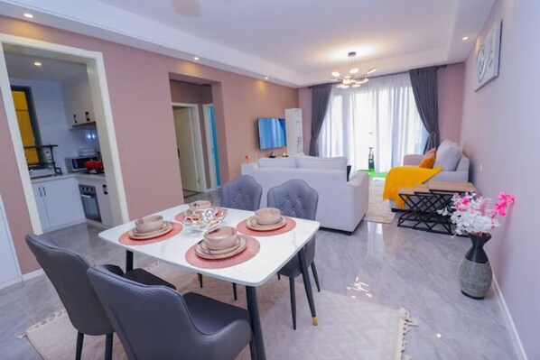 A modern living room with a dining area, a sofa, and a TV.