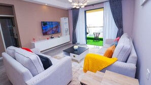 A modern living room with a sofa, coffee table, and a TV mounted on the wall. - Lymack Suites, 1BR Fourways Junction , Kiambu Road (Nairobi)
