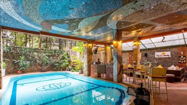 Ein Hallenbad mit blauem Logo, umgeben von einem Essbereich mit Tischen und Stühlen, und eine Wand mit dem Schild 'That room'.