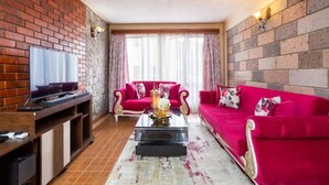 Ein Wohnzimmer mit Backsteinwand, einem roten Sofa, einem Couchtisch und einem Fernseher auf einem Holzboden.