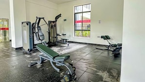 A gym with exercise equipment, a bench, and a window with a view of the outside.