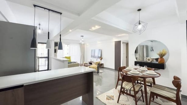 A modern kitchen with a central island, pendant lighting, and a dining area with a round table and chairs.