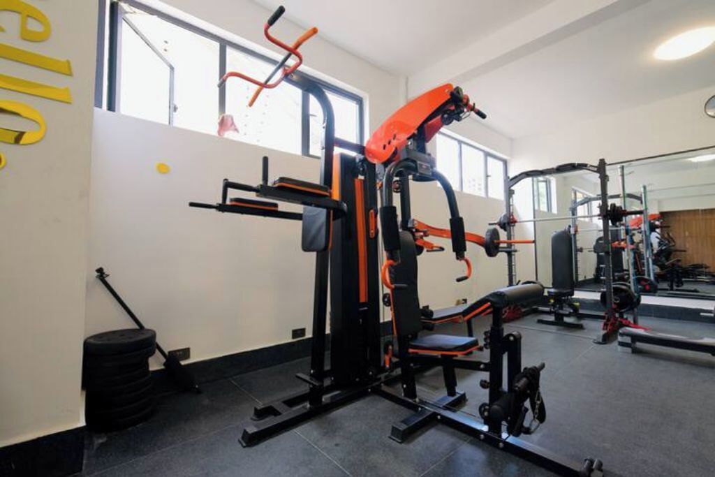 Un gimnasio con equipo de levantamiento de pesas, un espejo y un ventanal grande.