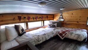 A cozy cabin interior with a bed, a bench, and a small table.