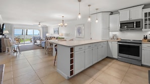 A spacious kitchen with white cabinetry, a large island, and a view to the outdoors. - Sandpiper 108 (New Smyrna Beach)