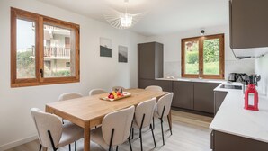 Eine moderne Küche mit einem Holzespeisetisch, sechs Stühlen und Blick auf einen Balkon.
