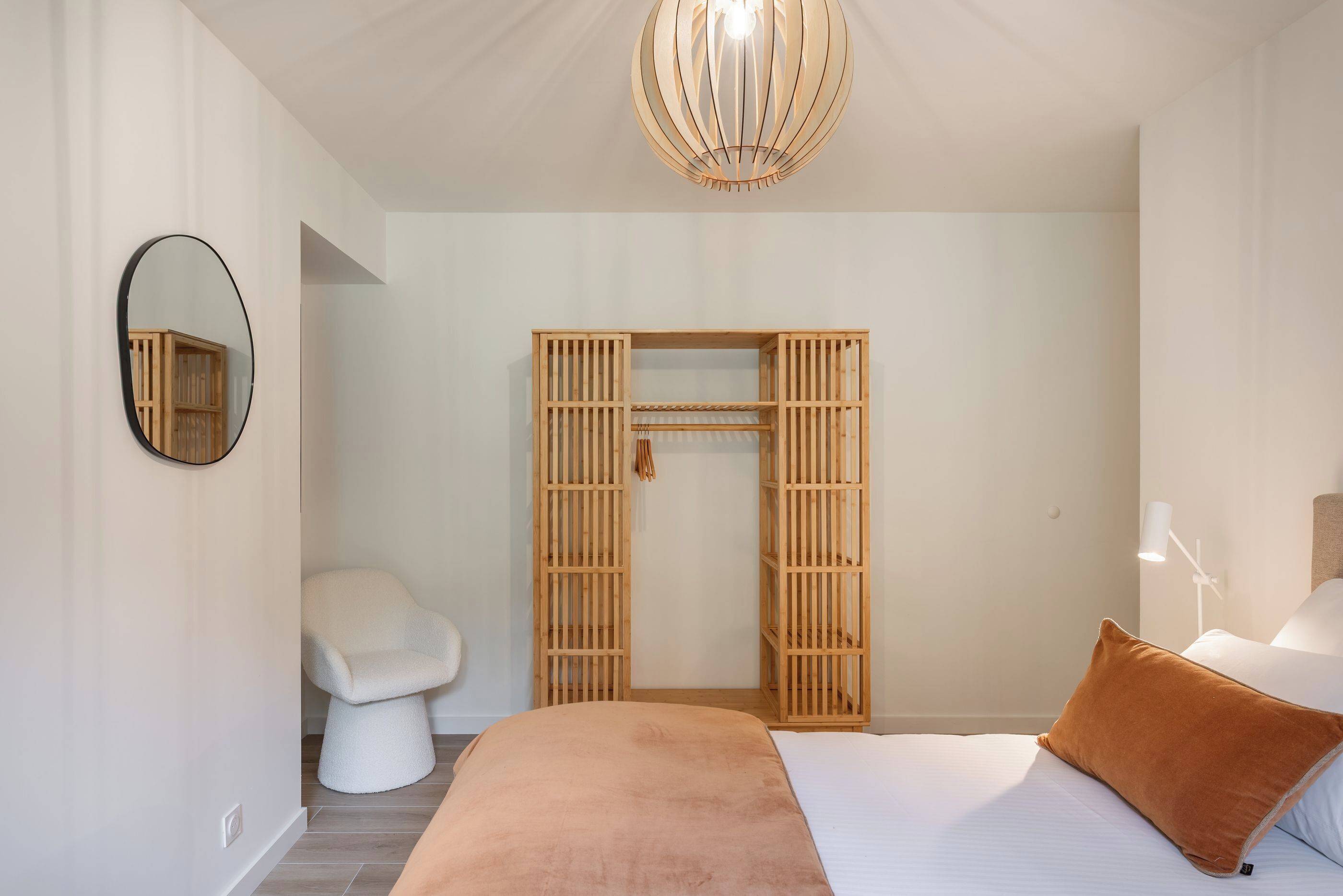 Ein Schlafzimmer mit Bett, Nachttisch, Kleiderschrank, Spiegel und Pendelleuchte.