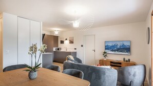 A modern living space with a dining area, kitchen, and a large window with a mountain view.