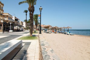 A beachside promenade with palm trees, beach umbrellas, and lounge chairs. - 50m from the beach | Calle San Enrique 3-2 (Los Alcázares)