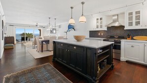 A modern kitchen with dark cabinetry, a large island, and pendant lighting. - Sandpiper 508 (New Smyrna Beach)