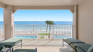 A balcony with a view of the beach and pool, featuring lounge chairs and a railing. - Sandpiper 508 (New Smyrna Beach)