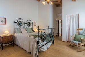 Un dormitorio con cama, mesitas de noche, una mecedora y suelo de madera.