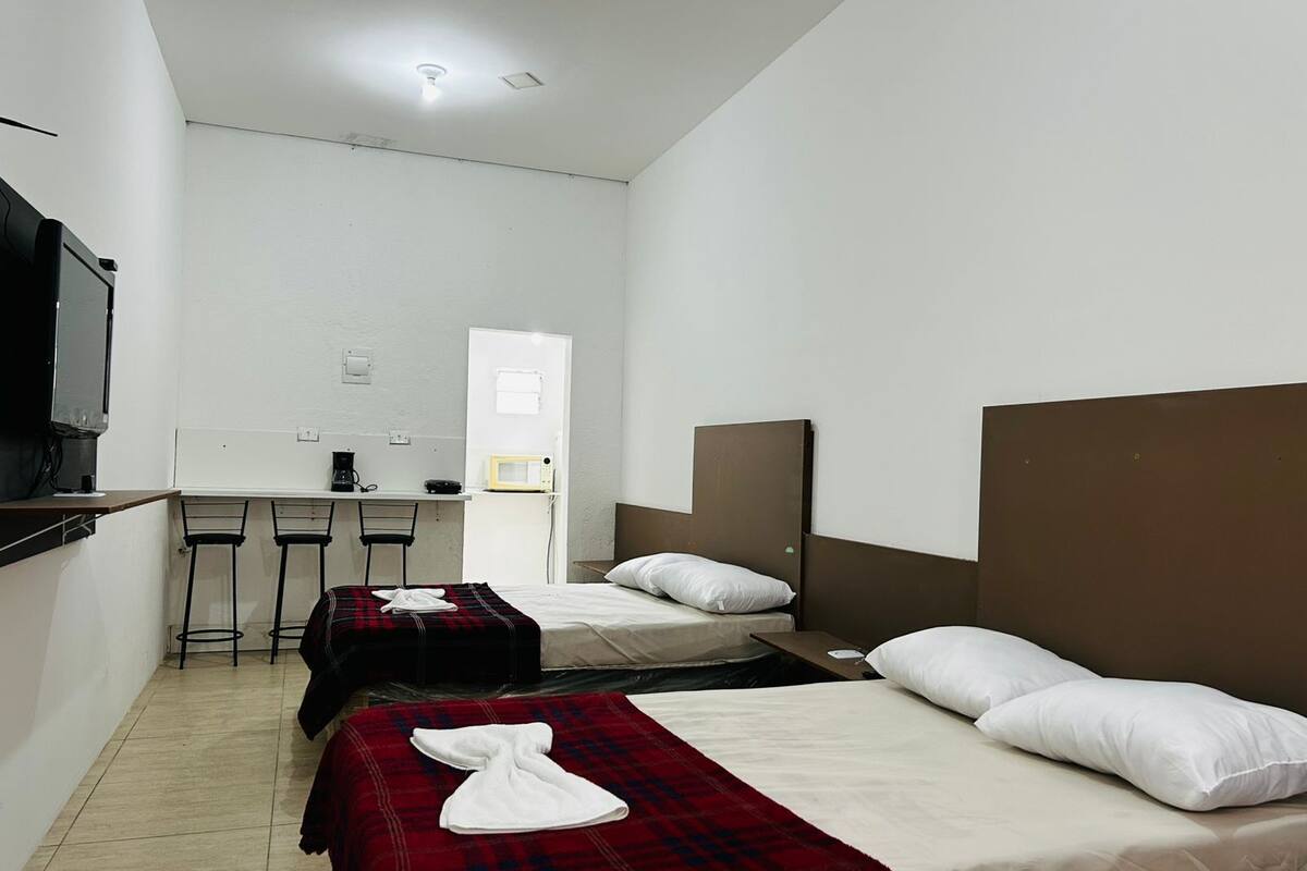 Habitación de hotel con dos camas, un escritorio, una silla, microondas y televisión.