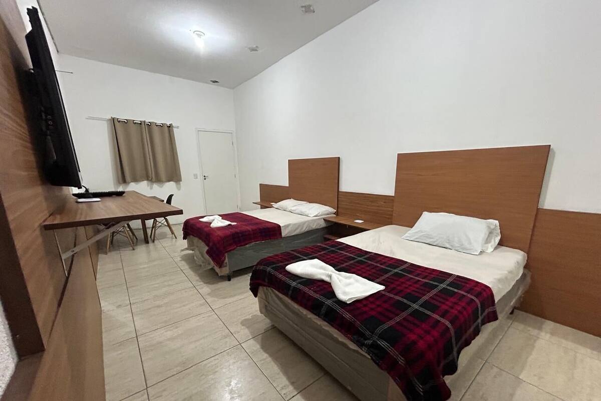 Una habitación de hotel con dos camas, un escritorio y una televisión.