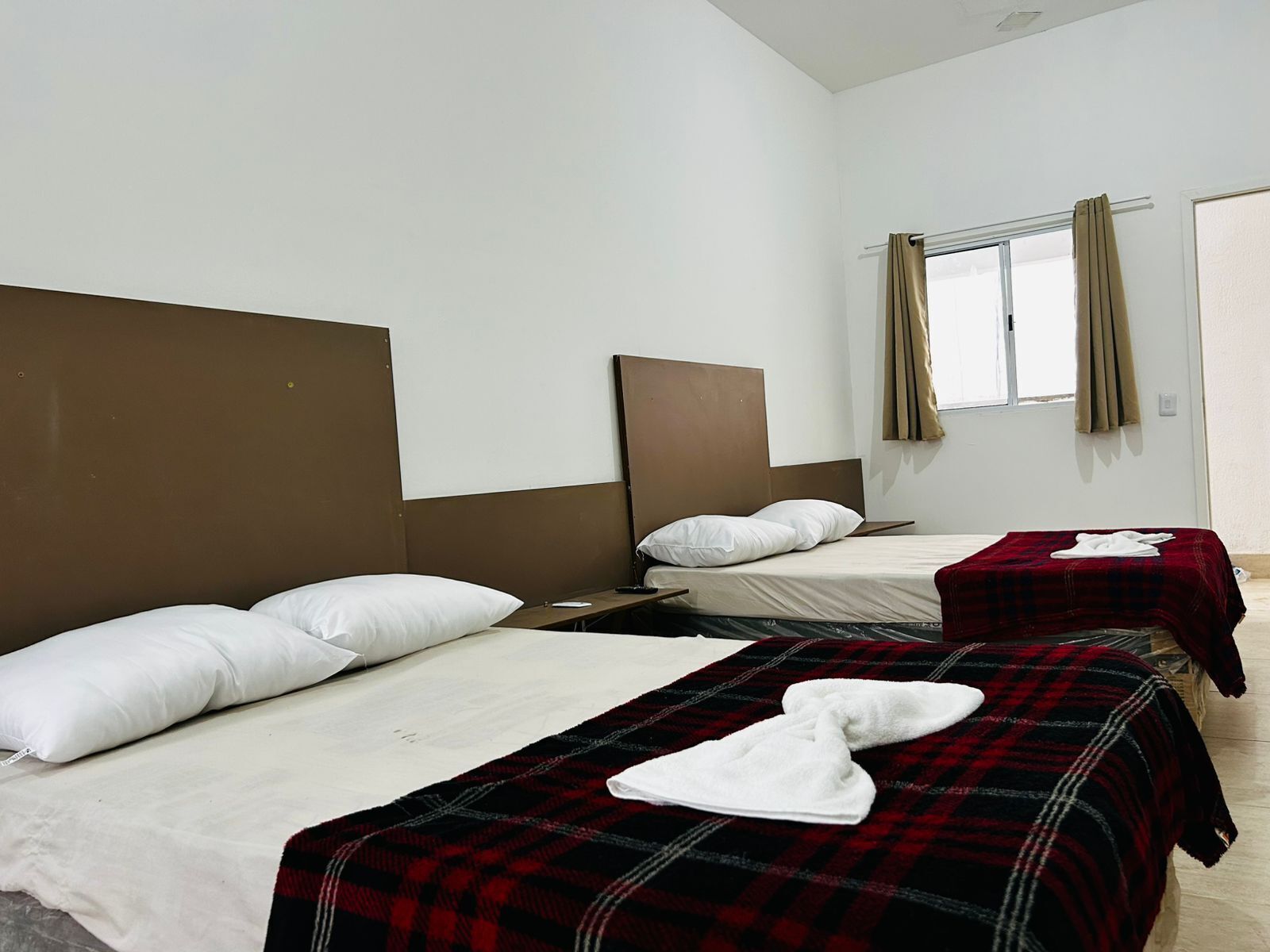 A hotel room with two single beds, each with a headboard and a bedside table.